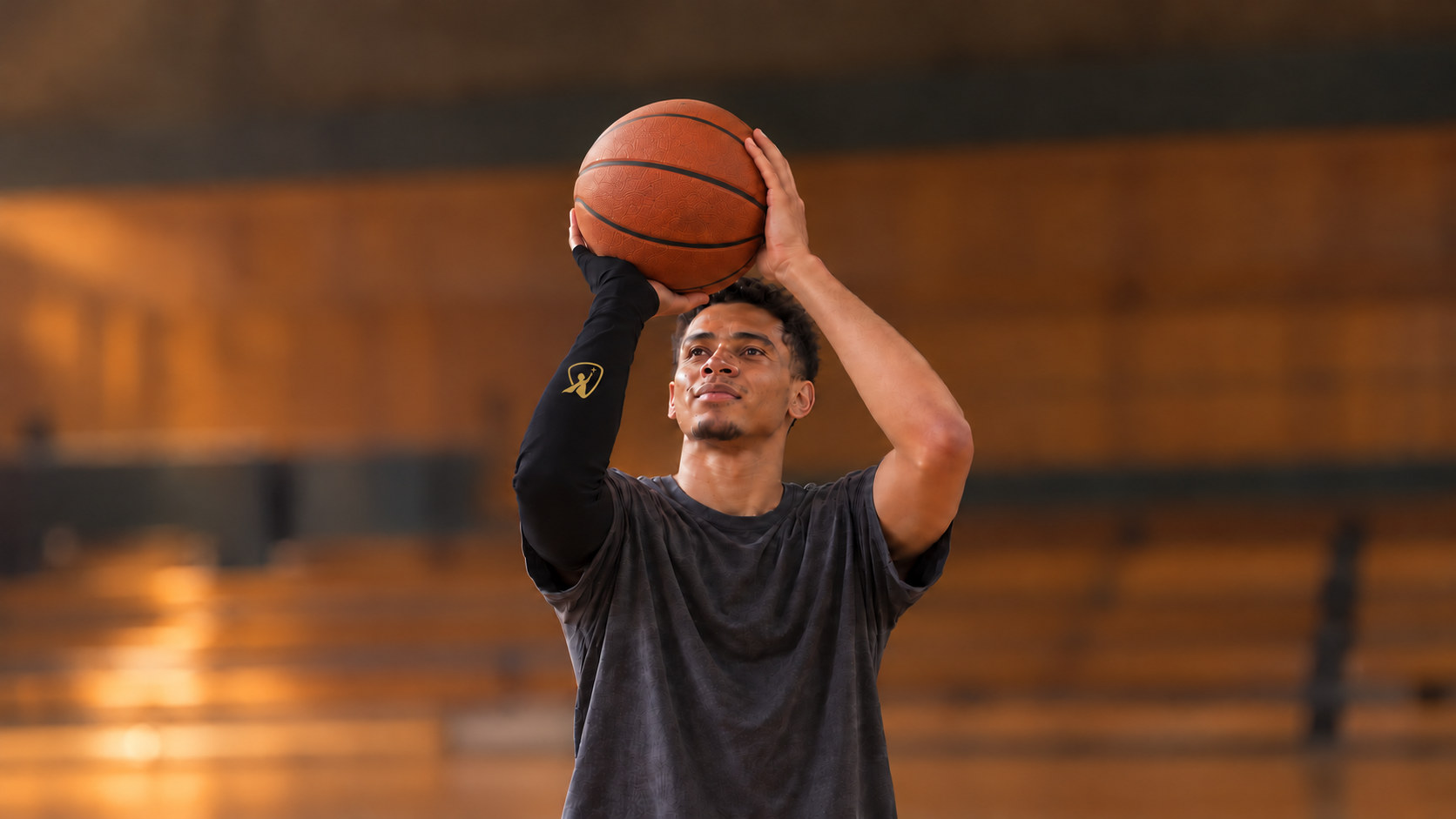 A basketball player at his free-throw set point, the black Betta sleeve with its gold Betta logo on his shooting arm